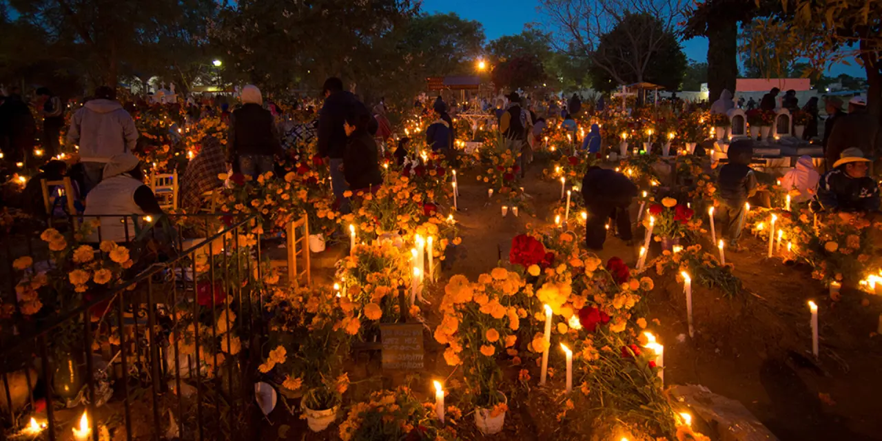 Día de Muertos celebration in Oaxaca at night with candles and marigolds